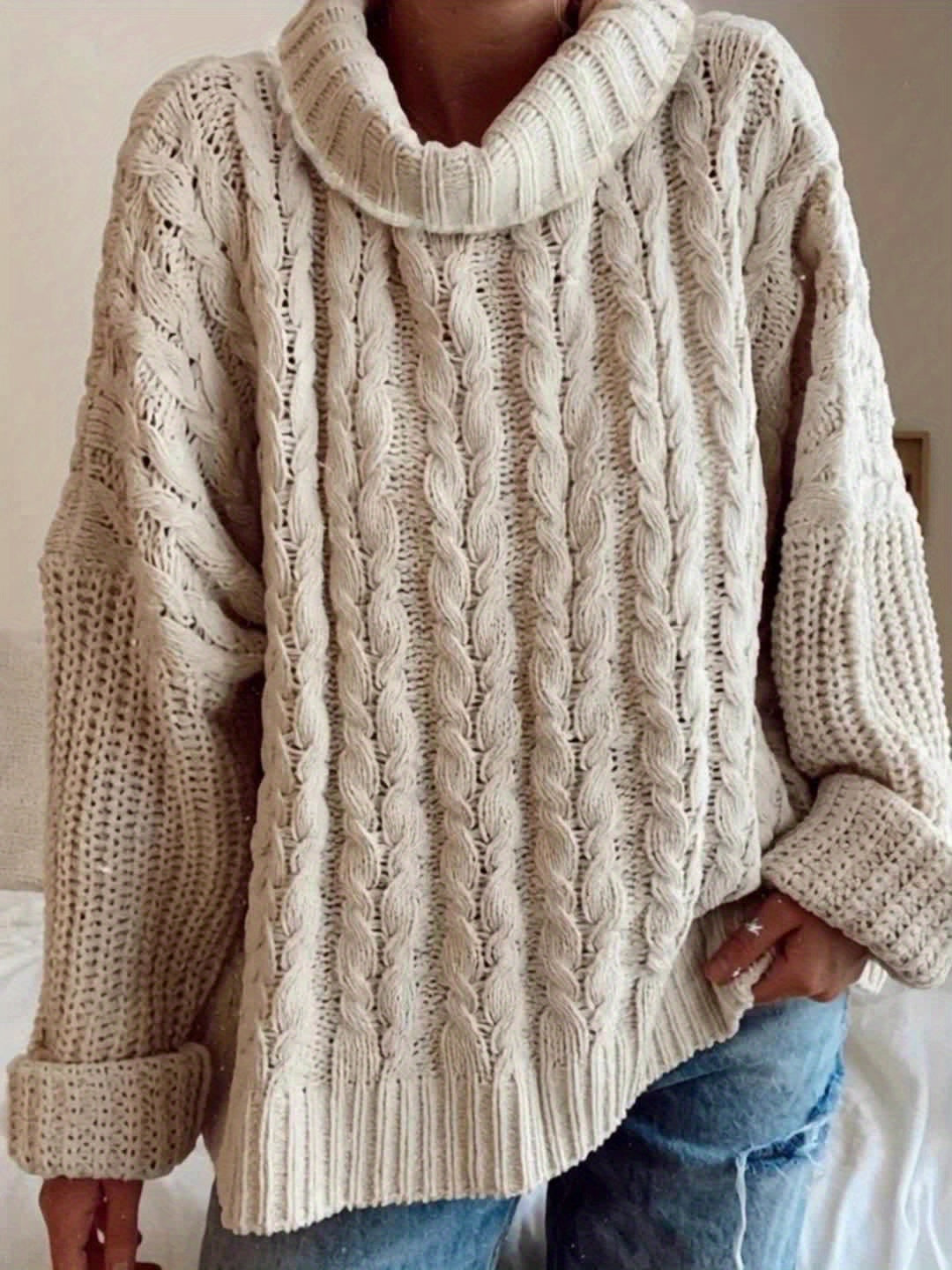 Beige cable knit sweater worn by a person, with a neutral background