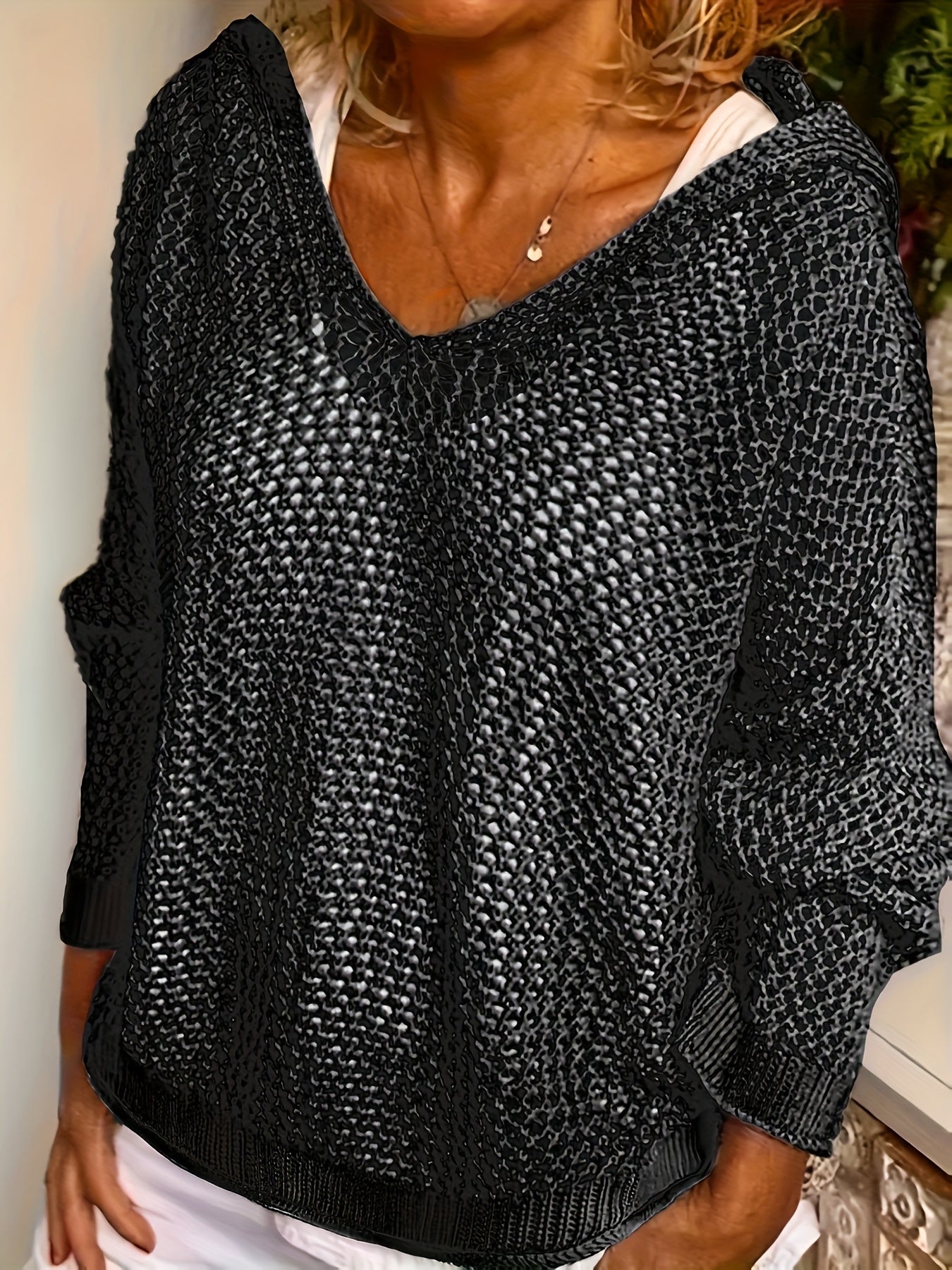Person wearing a black textured sweater with a blurred background