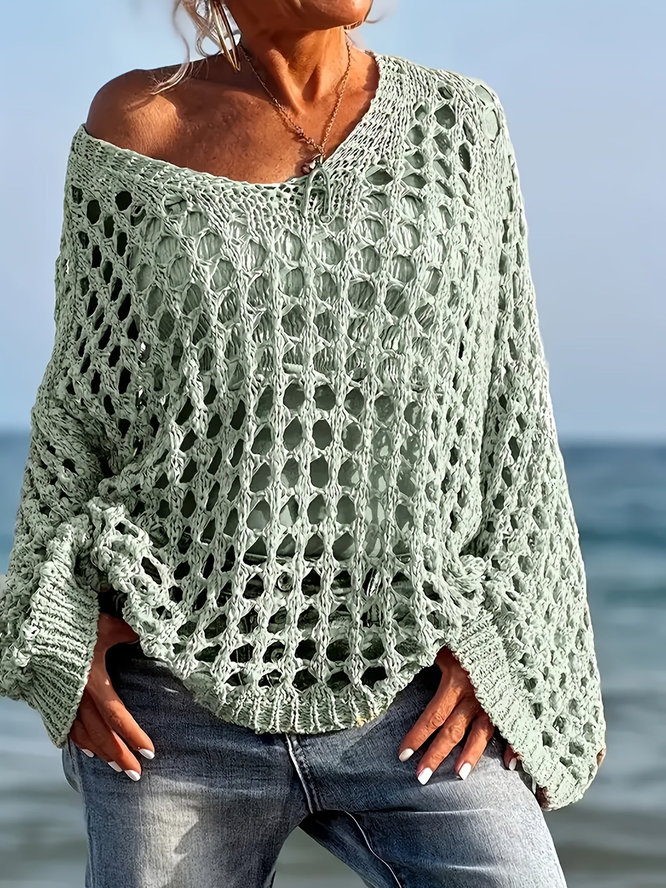Person wearing a green crochet sweater by the ocean
