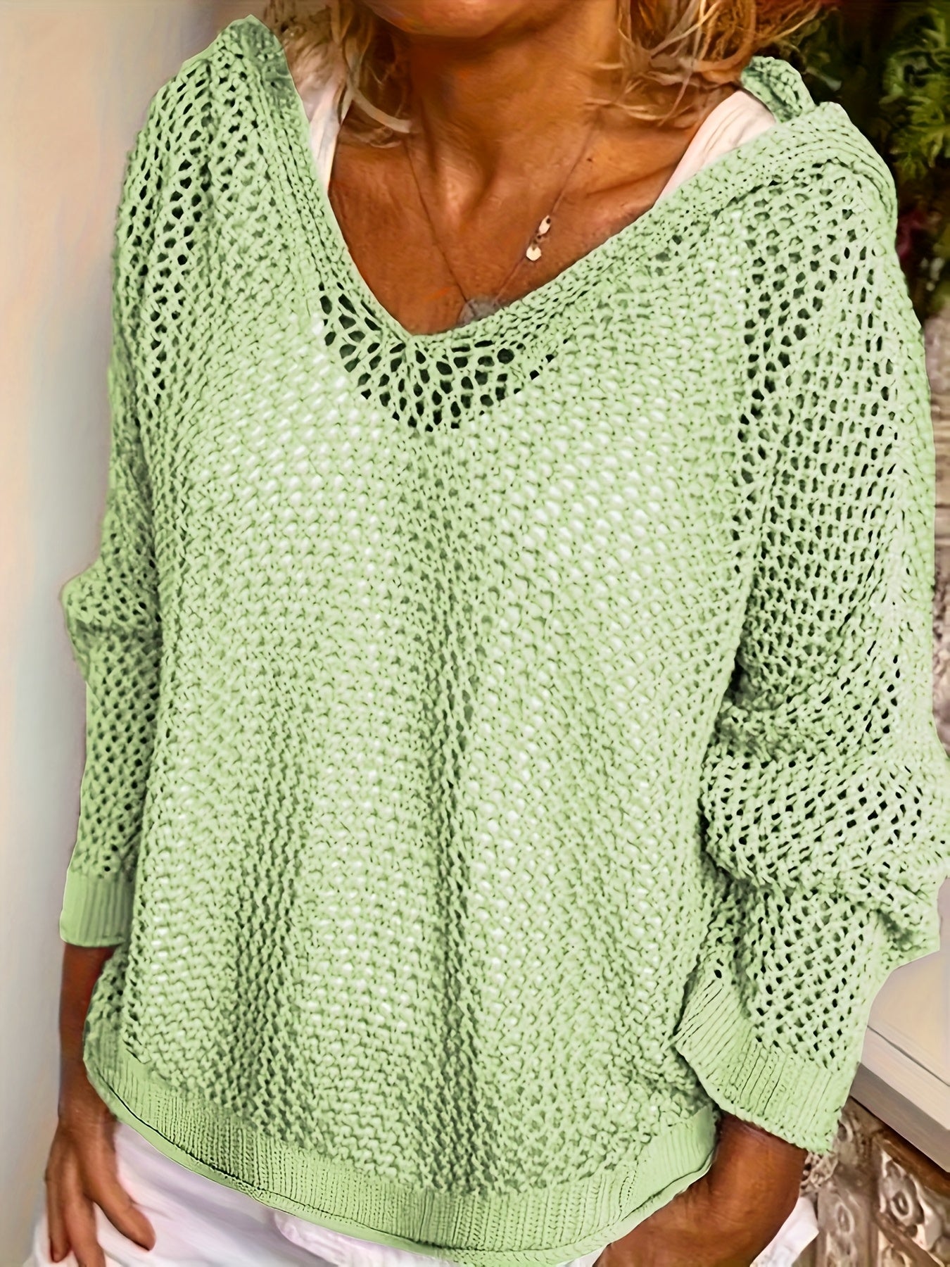 Green knitted sweater worn by a person, with a neutral background