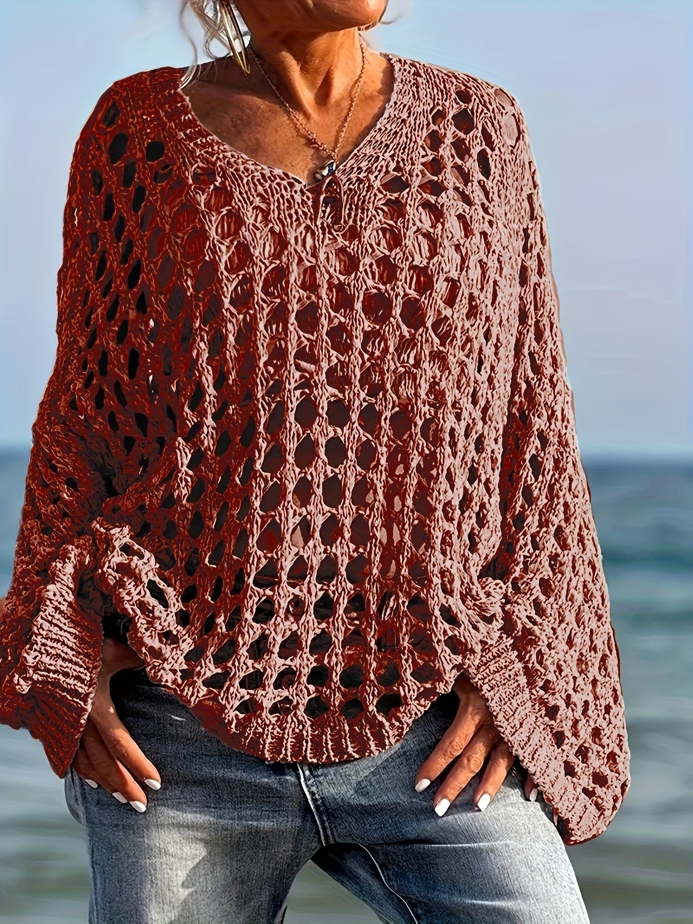 Person wearing a brown crochet sweater by the ocean