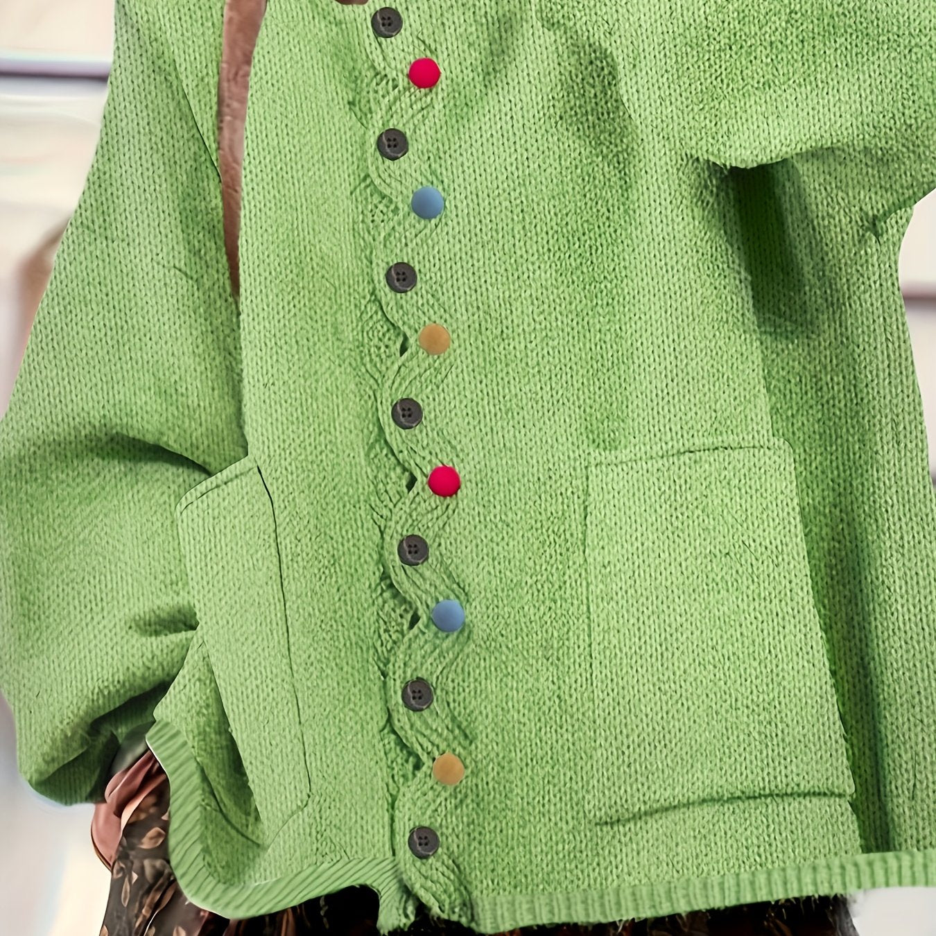 Green knitted cardigan with colorful buttons on a neutral background