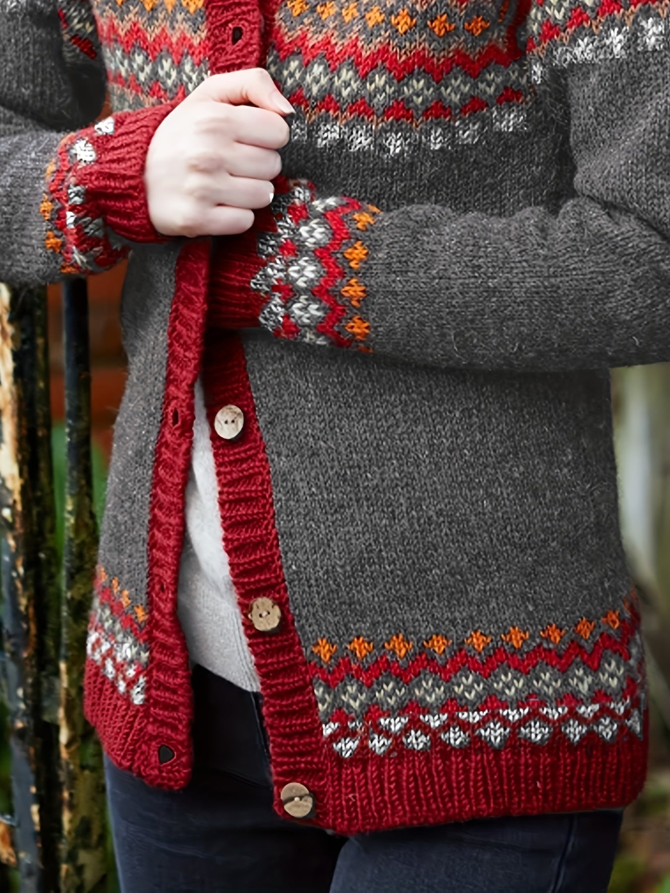 Person wearing a gray cardigan with red and multicolor patterned trim.