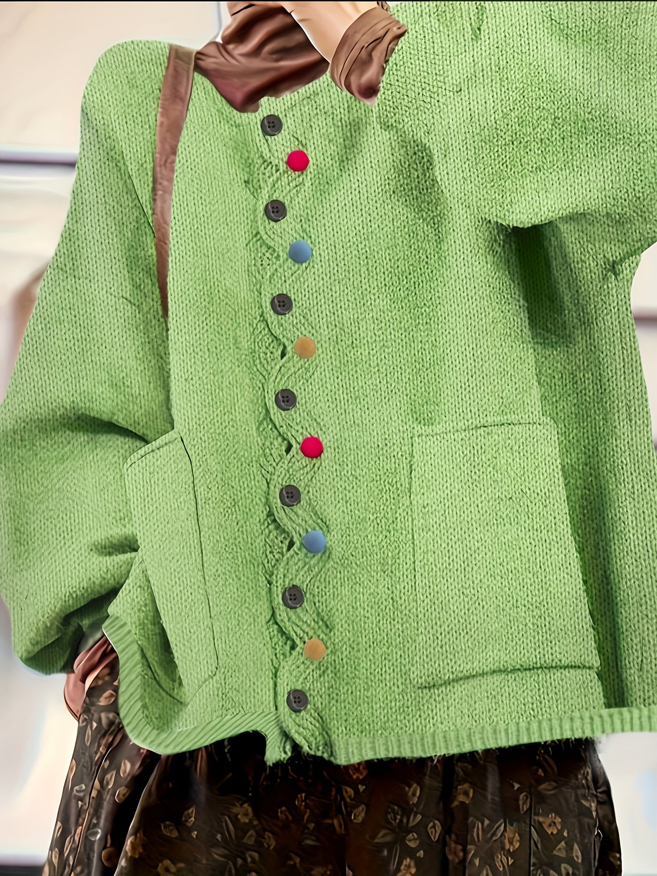Green knitted cardigan with colorful buttons worn by a person.