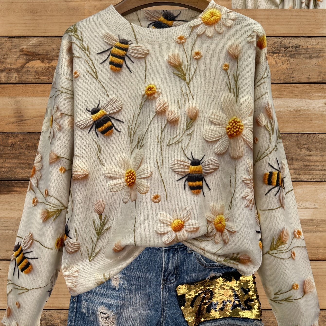 Sweater with floral and bee designs on a wooden background