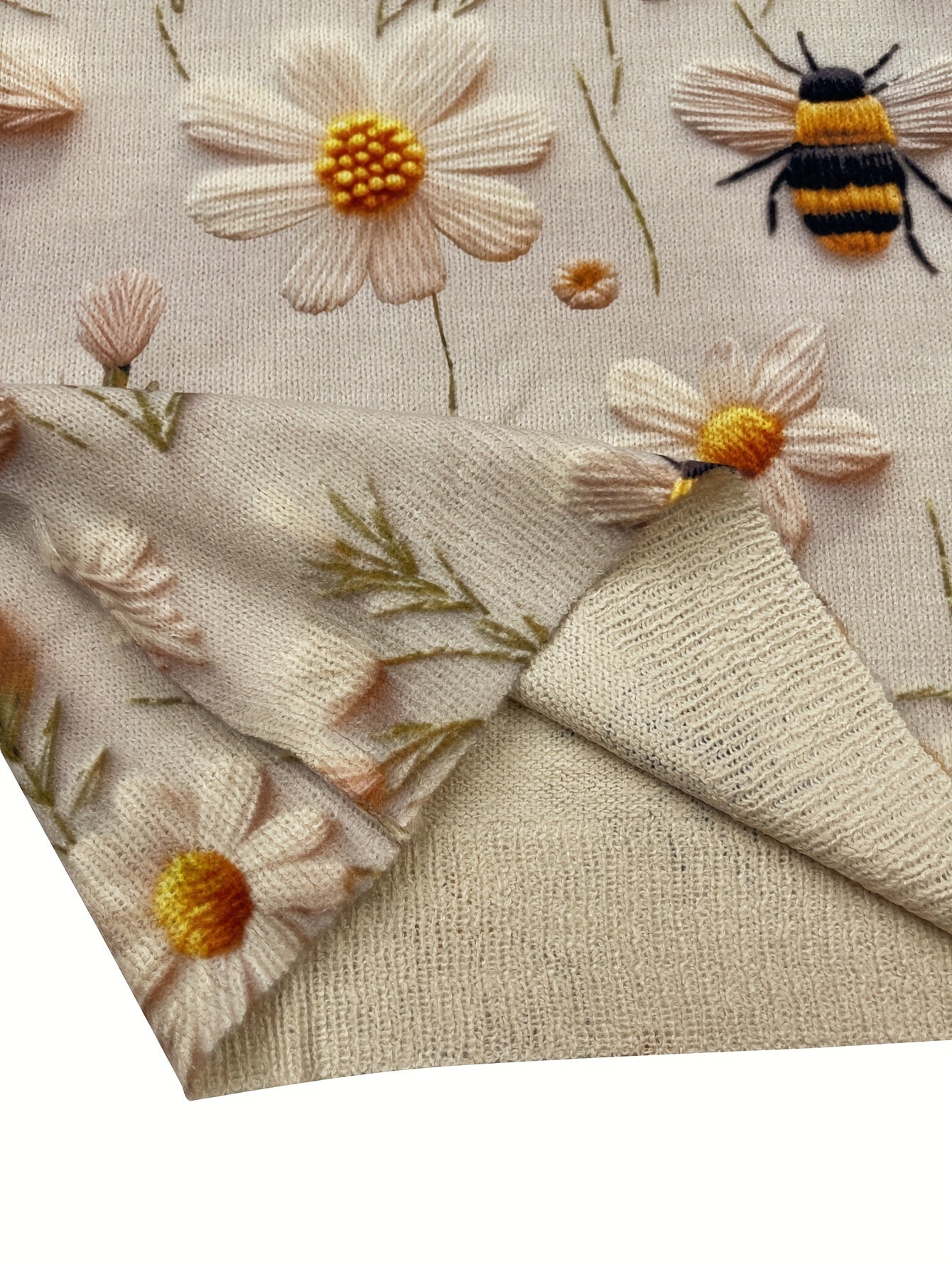 Close-up of embroidered fabric with flowers and a bee on a beige background