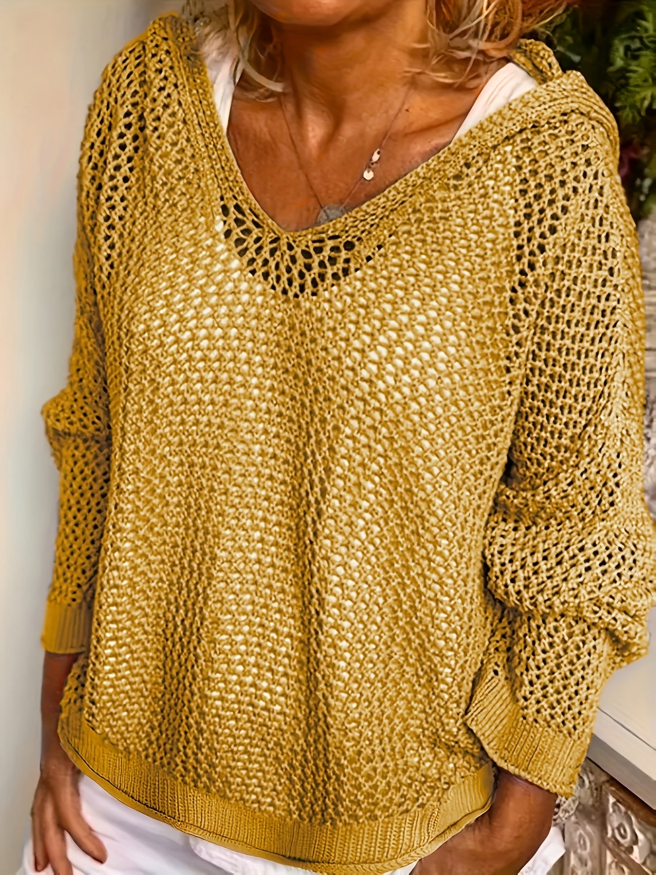 Person wearing a mustard yellow knitted sweater with a white shirt underneath.