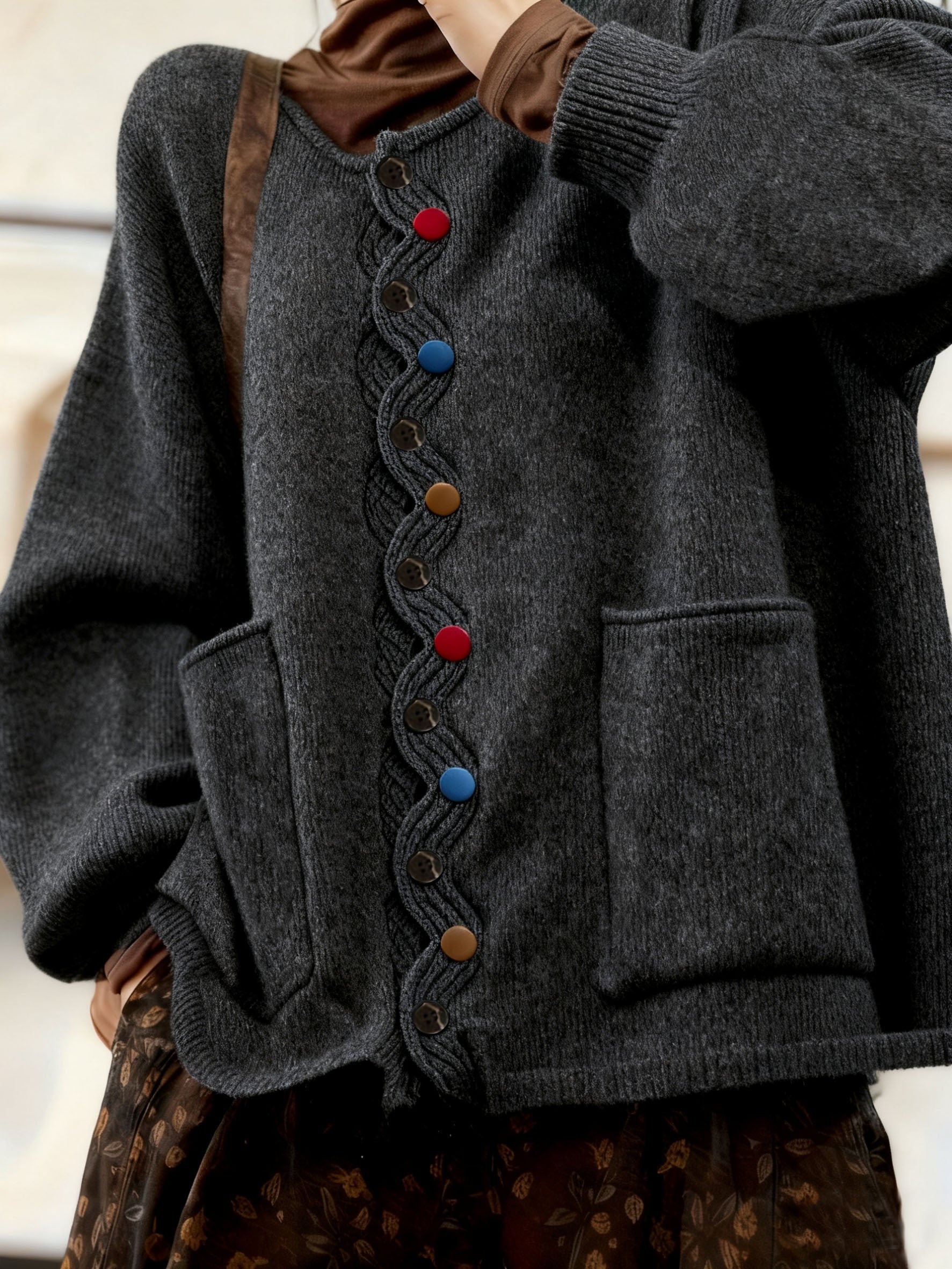 Dark gray cardigan with colorful buttons on a neutral background