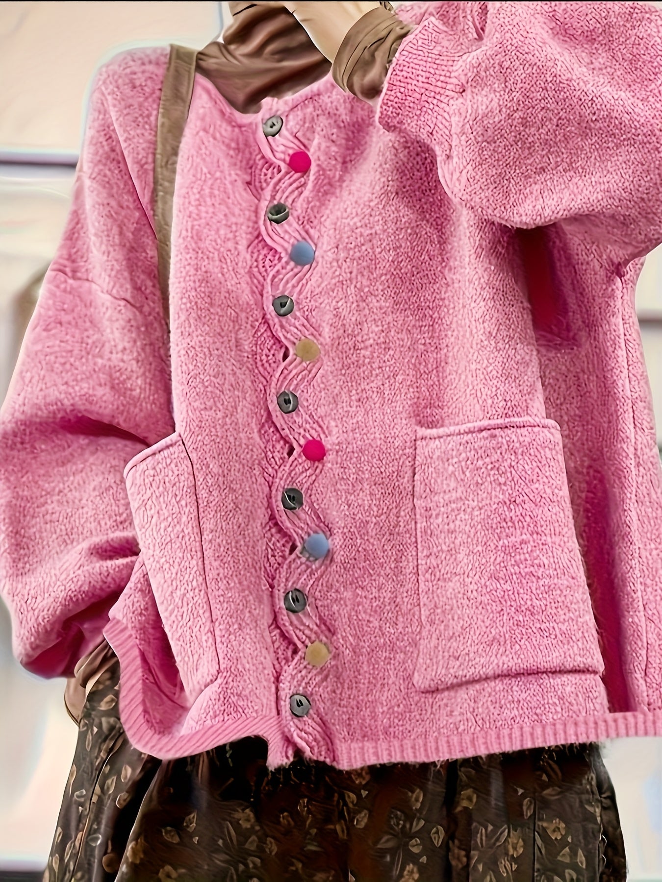 Close-up of a pink cardigan with colorful buttons on a neutral background