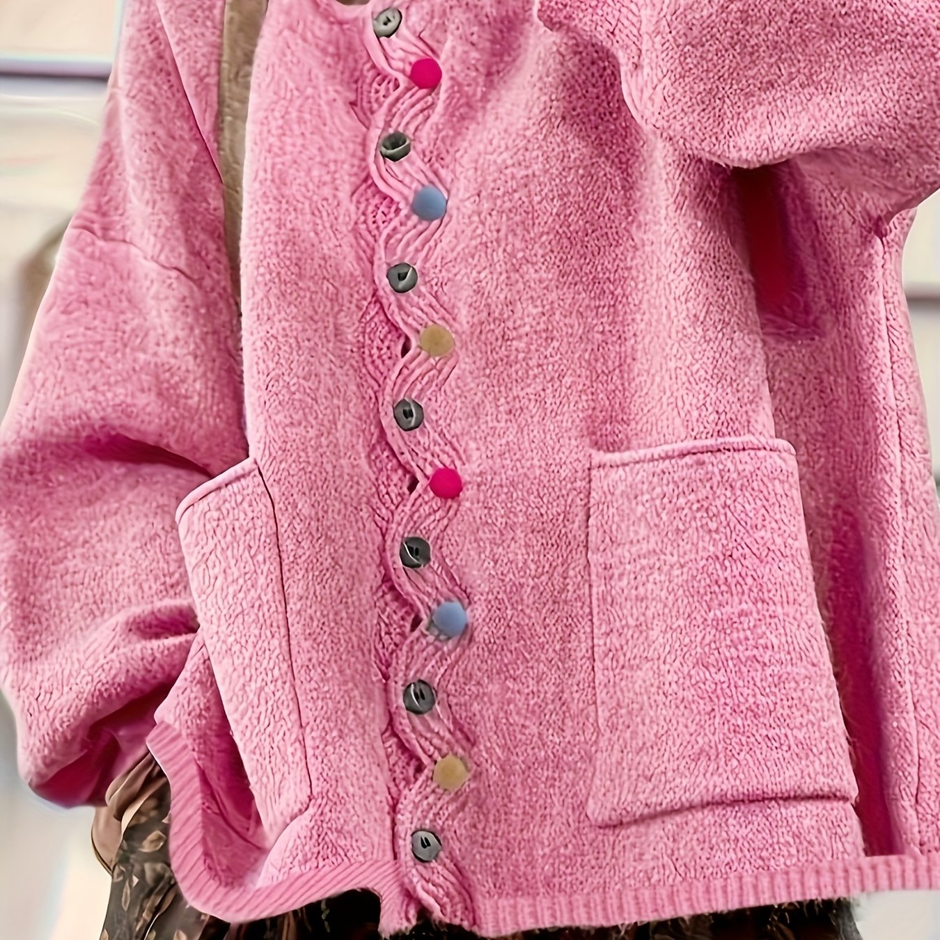 Close-up of a pink cardigan with colorful buttons on a blurred background