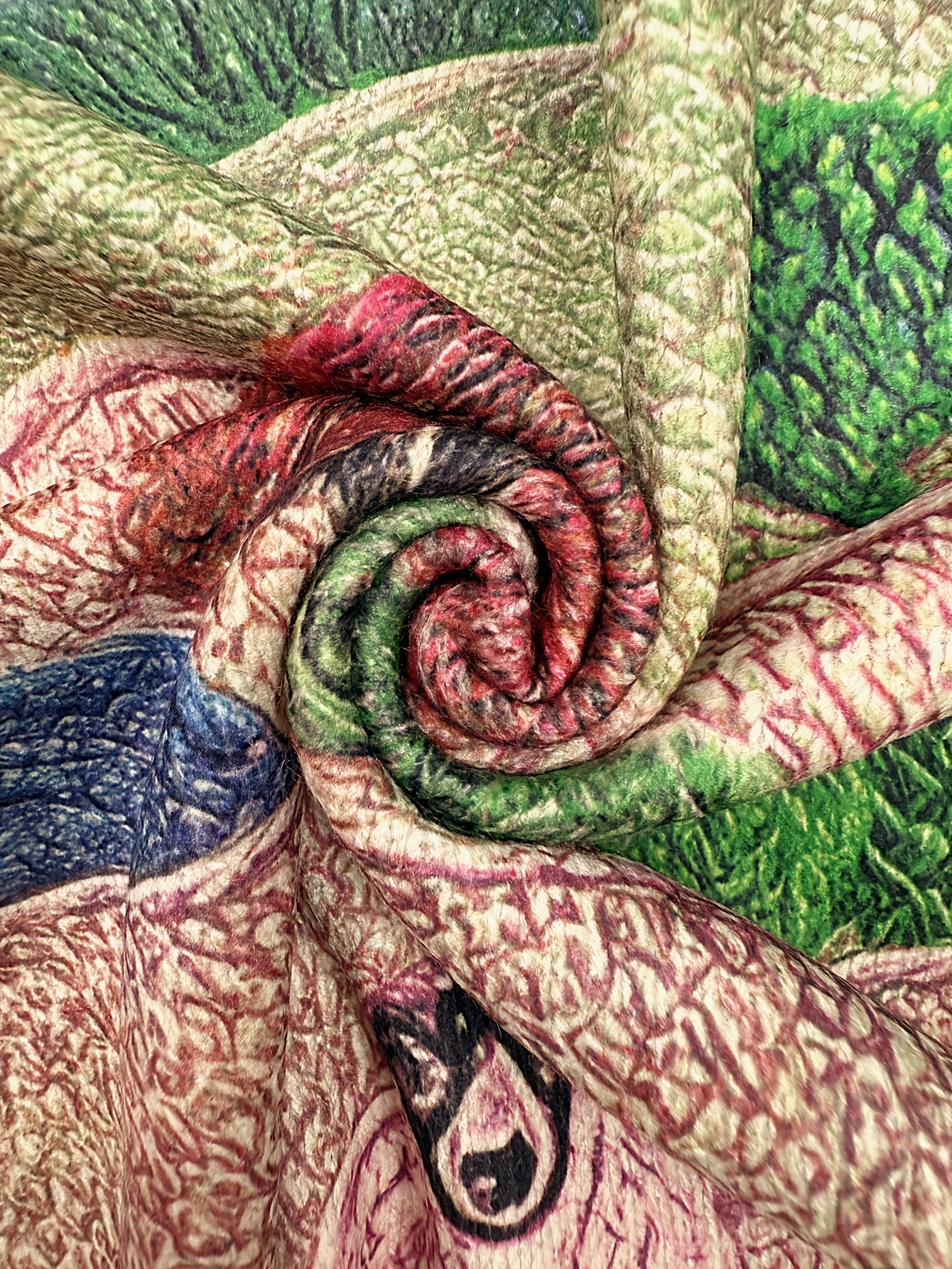 Close-up of a textured fabric with green, red, and pink colors.