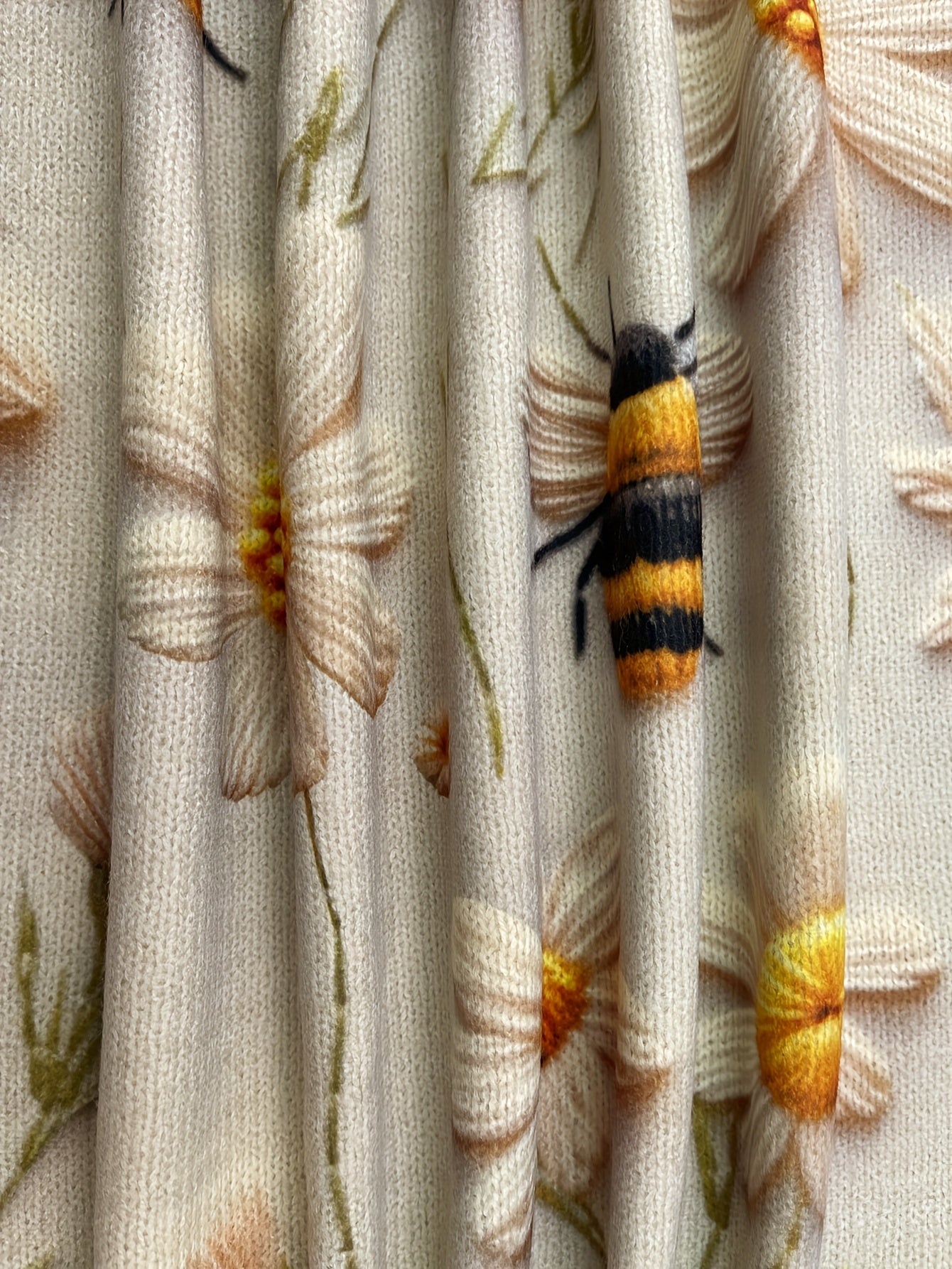 Close-up of a bee on floral fabric with a yellow and black striped pattern.
