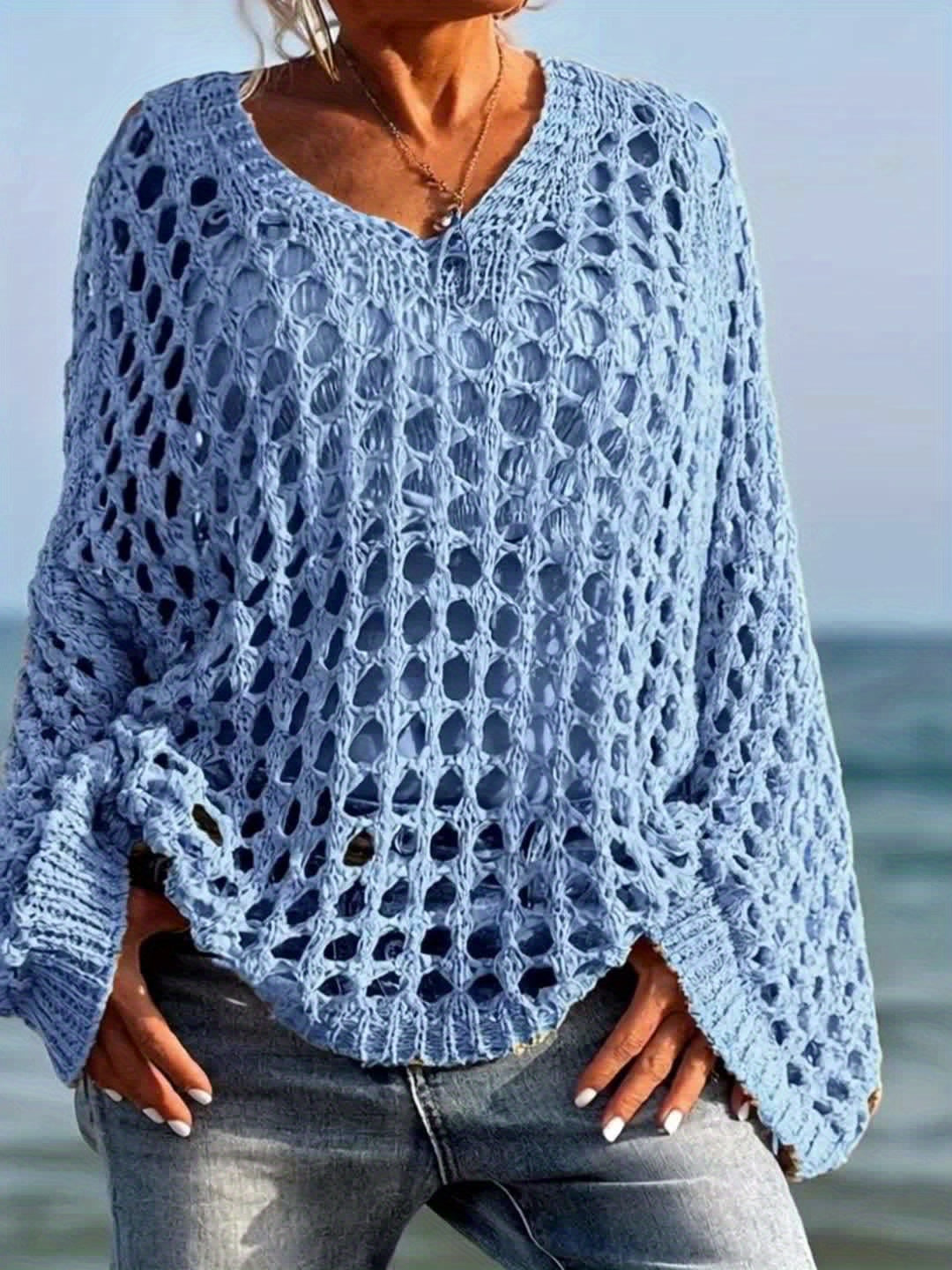Person wearing a blue crochet sweater by the ocean