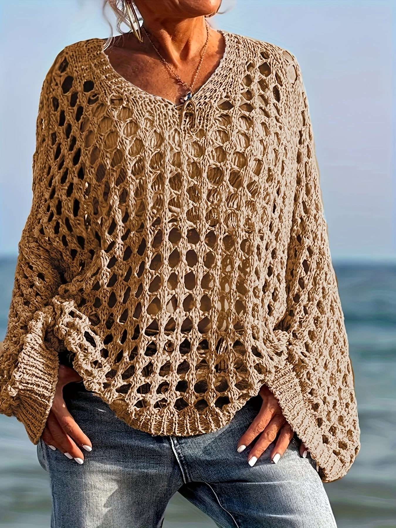 Person wearing a beige crochet sweater by the ocean