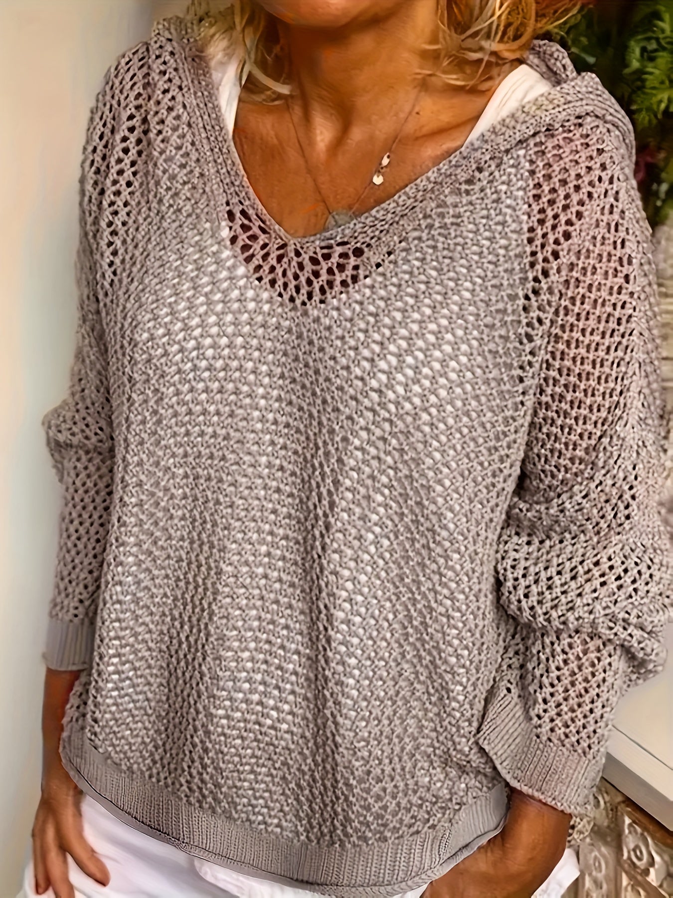 Person wearing a textured gray sweater with a white shirt underneath.