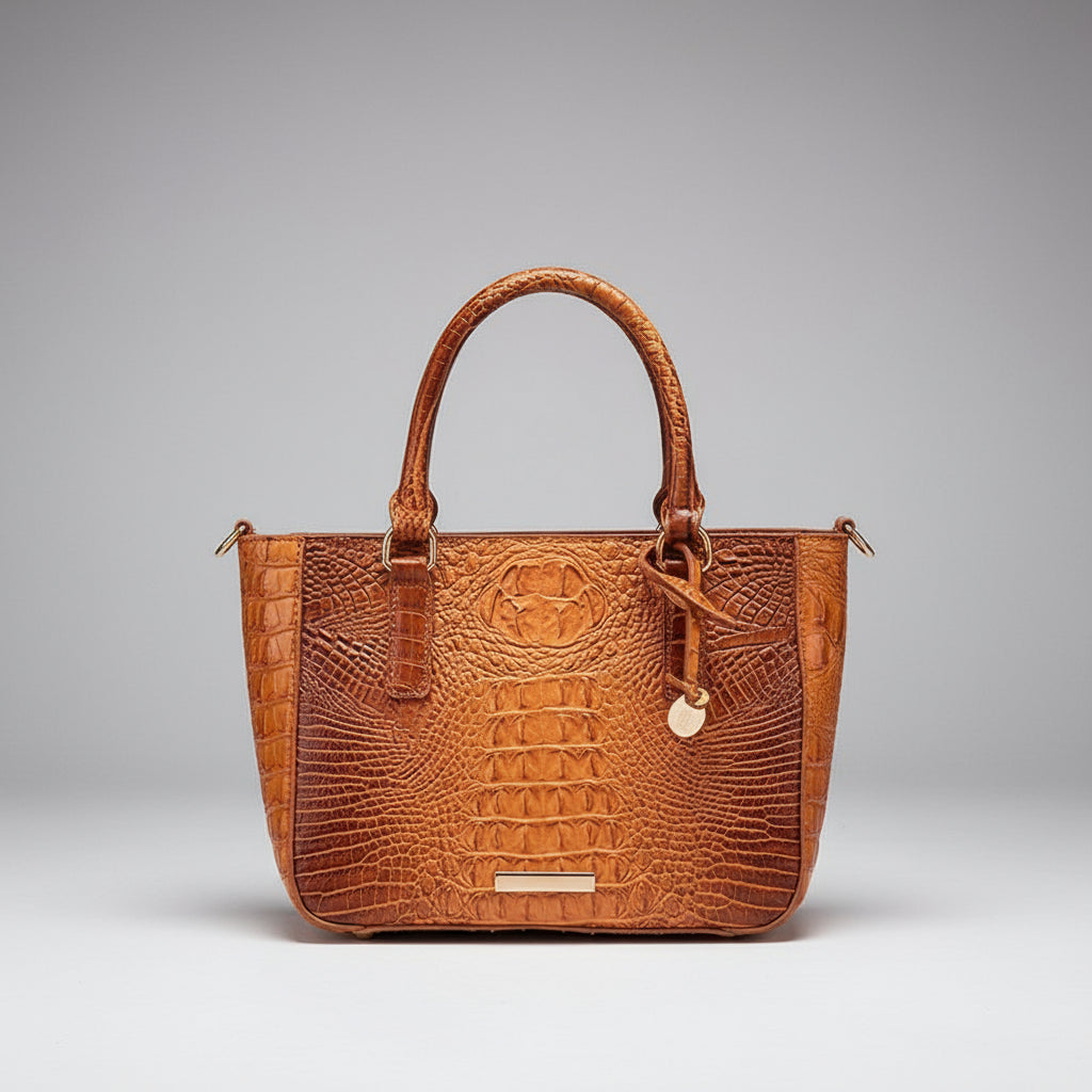 Brown leather handbag with crocodile texture on a wooden surface
