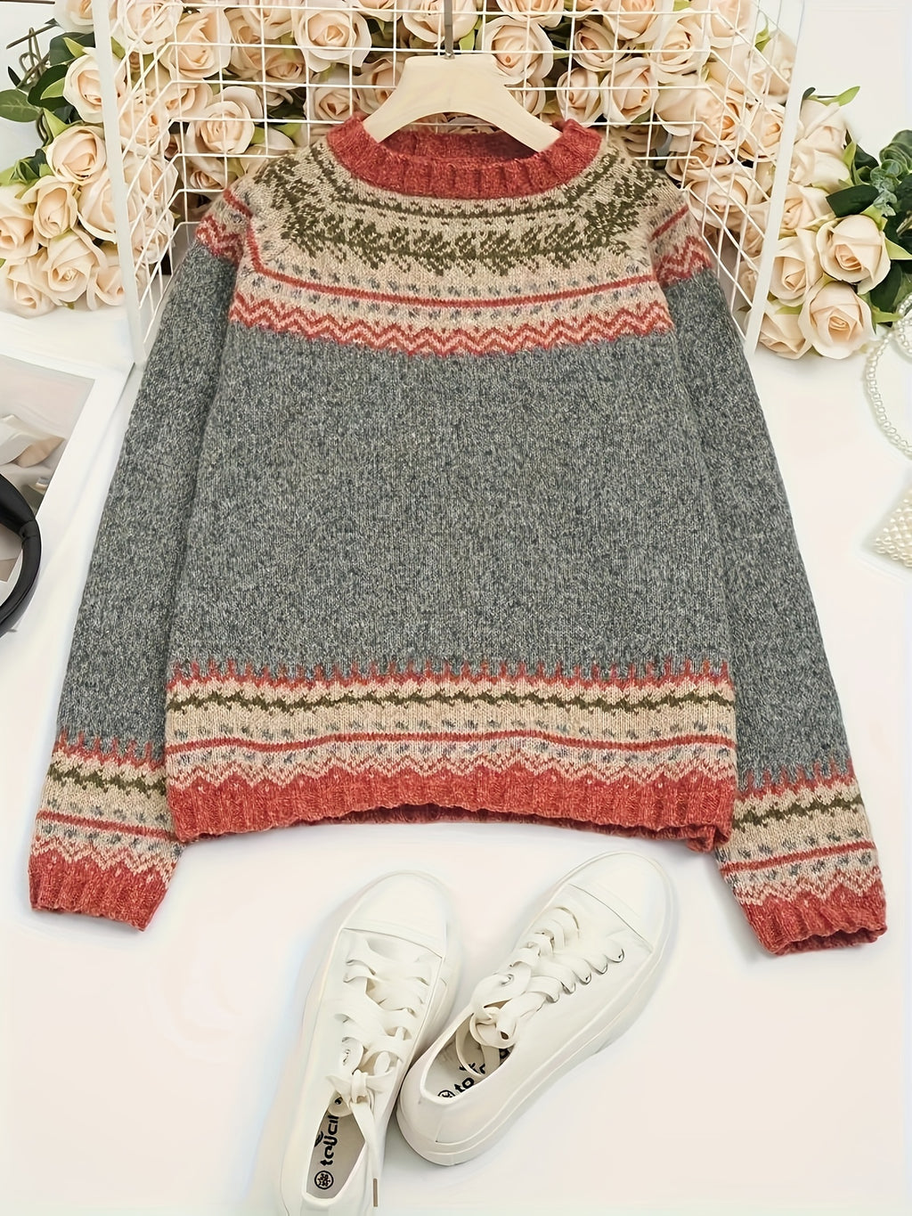 Gray sweater with colorful pattern and white sneakers on a light background