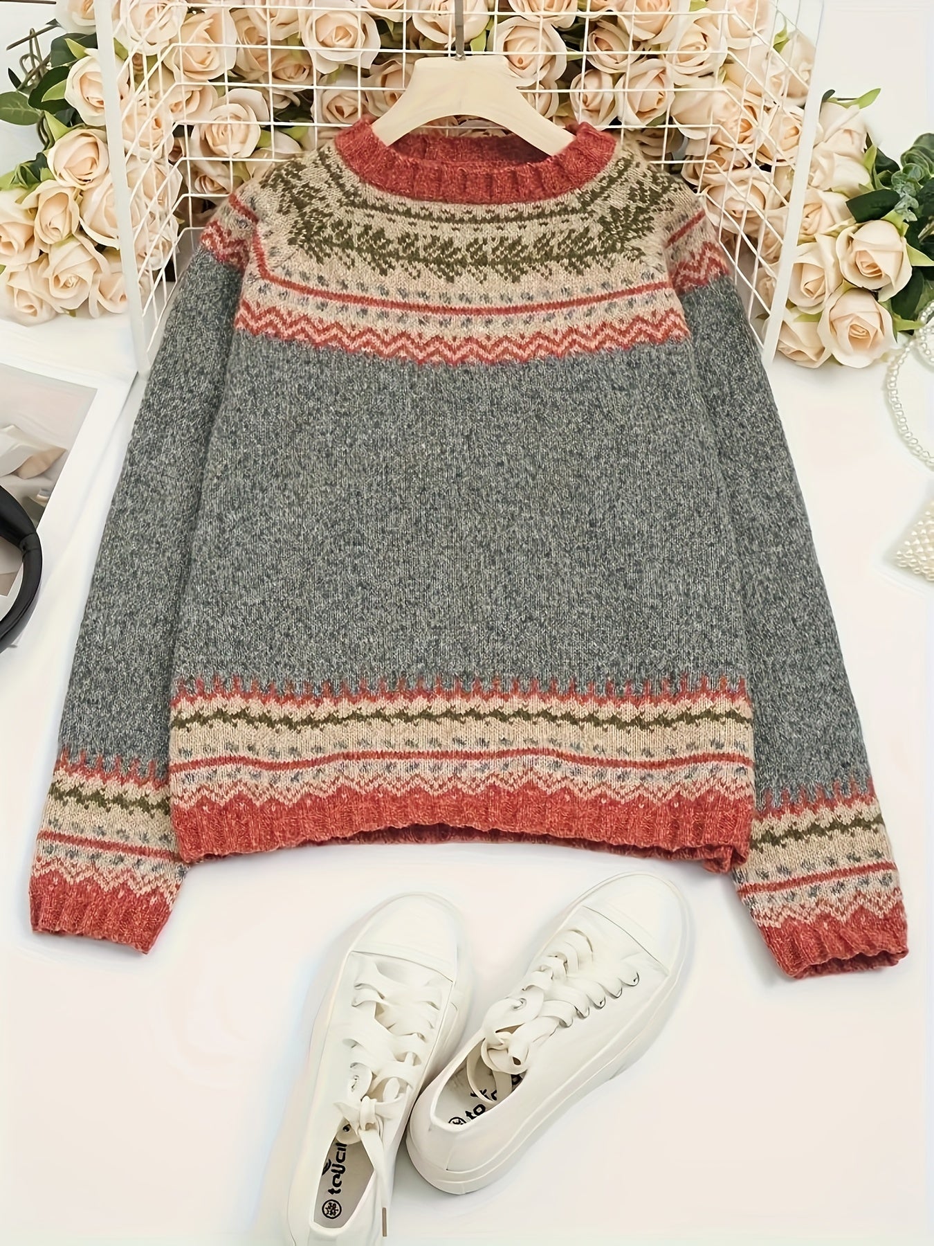 Gray sweater with colorful pattern and white sneakers on a light background