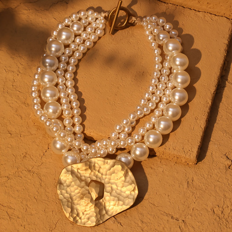 Pearl necklace with a gold pendant on a textured orange surface