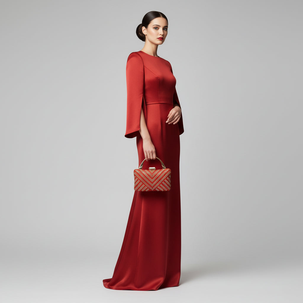 Orange handbag with gold detailing held by a hand against a light background