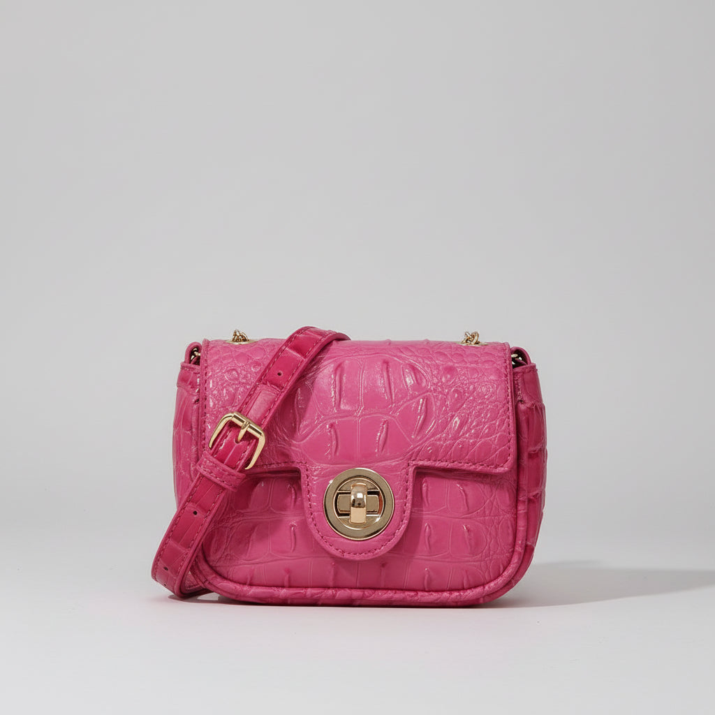 Pink textured handbag on a wooden surface with a dark background