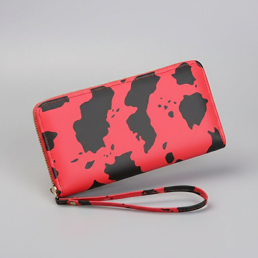 Red wallet with black patterns held by a hand on a wooden surface