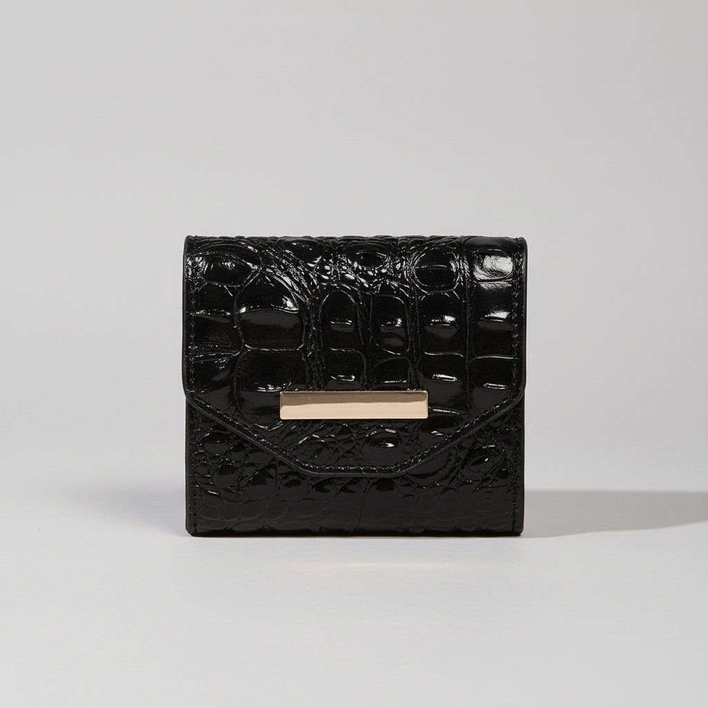 Black textured handbag with a gold clasp on a textured surface.
