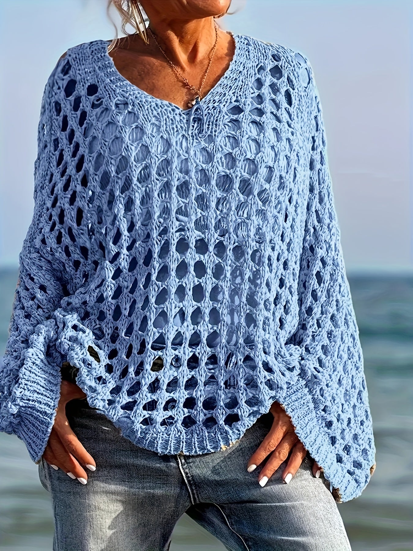 Person wearing a blue crochet sweater by the ocean