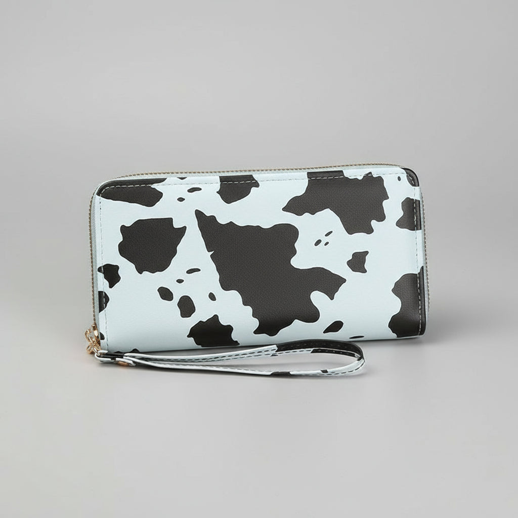 Cow print clutch held by a hand on a wooden surface