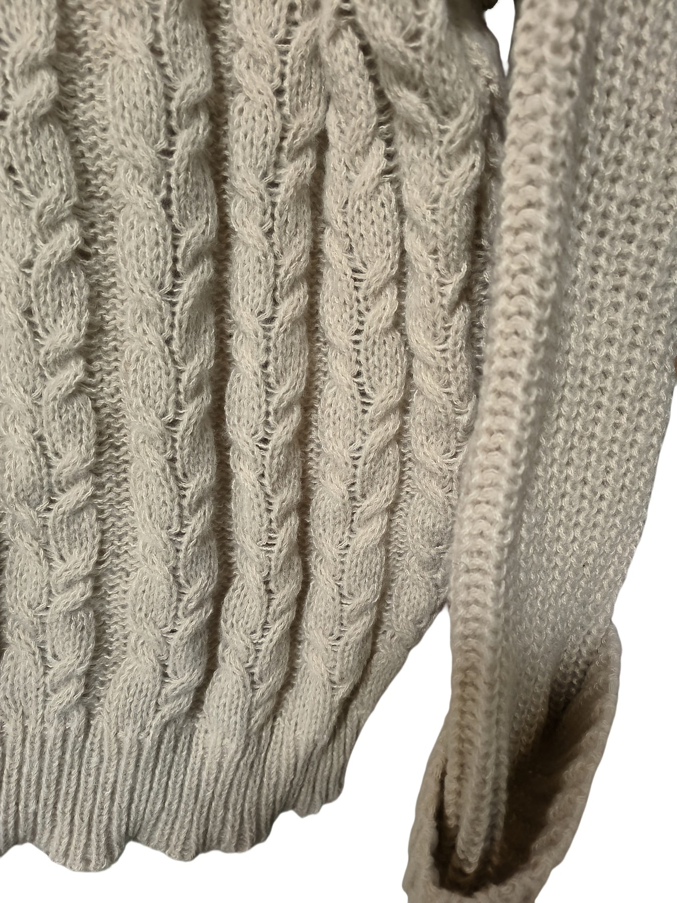 Close-up of a cable knit sweater with a neutral color on a white background