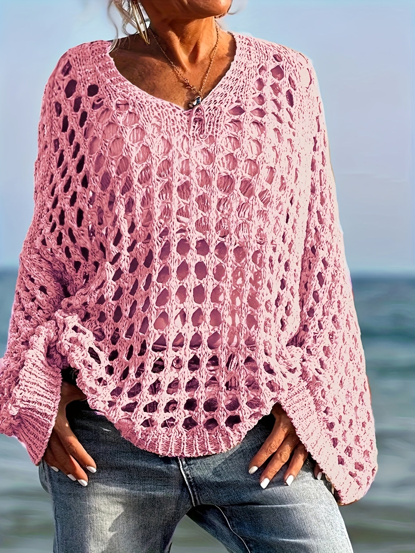 Person wearing a pink crochet sweater by the ocean