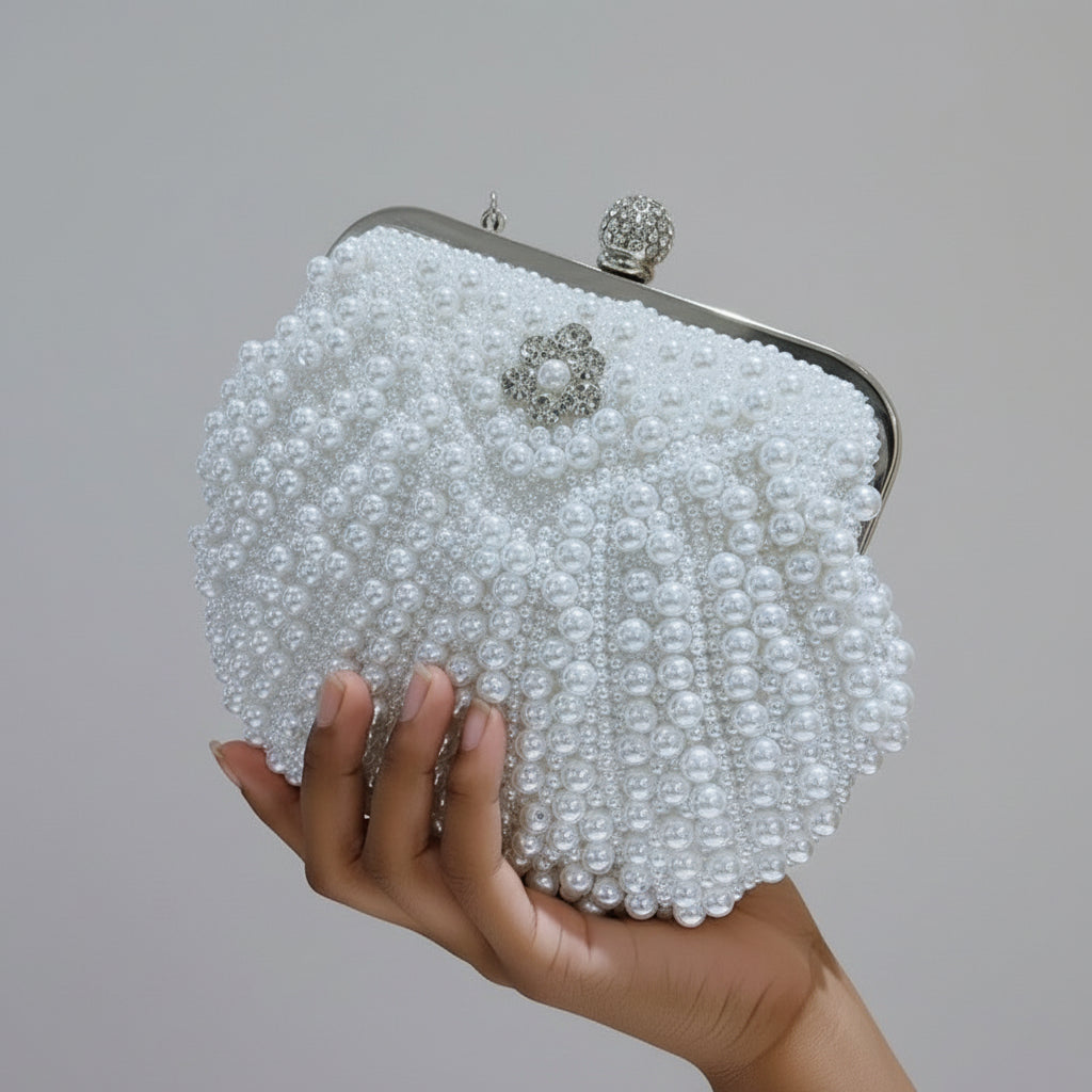 Pearl-handled clutch bag held by a hand against a blurred background
