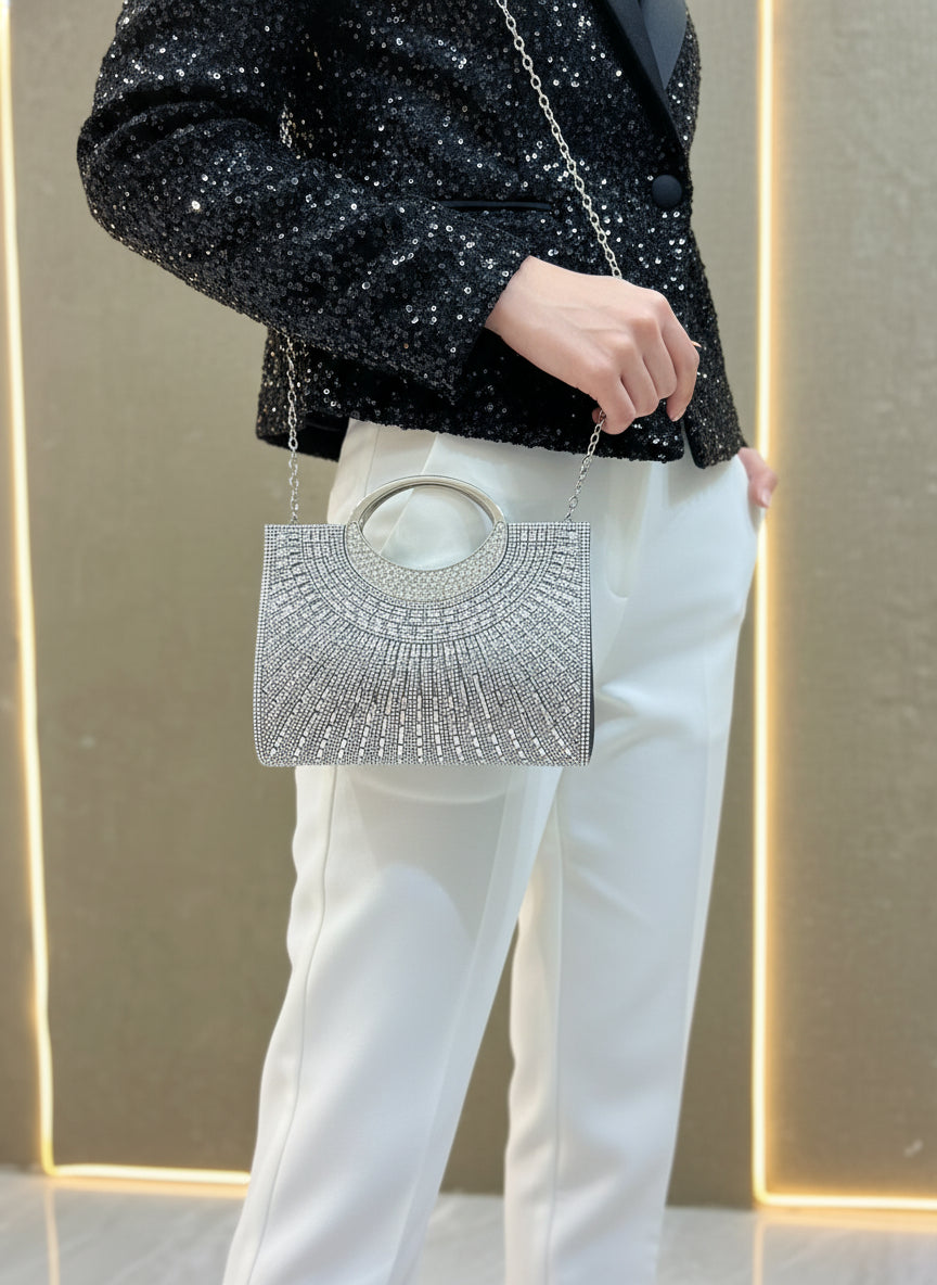 Silver handbag with intricate design held by a person wearing a black sequin outfit.