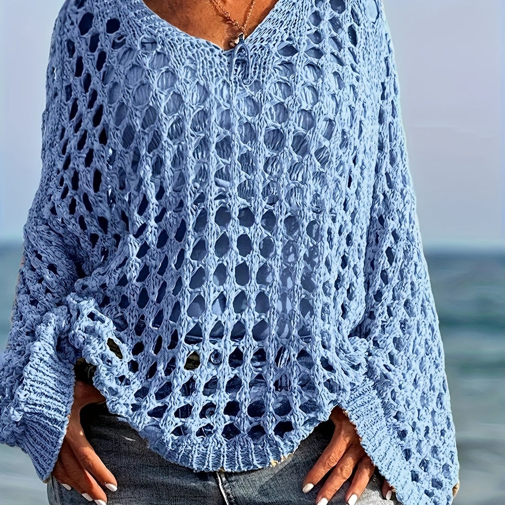 Person wearing a blue crochet sweater by the ocean