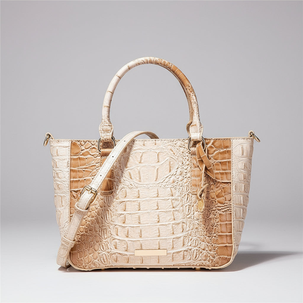 Beige crocodile-patterned handbag with a matching strap on a dark background