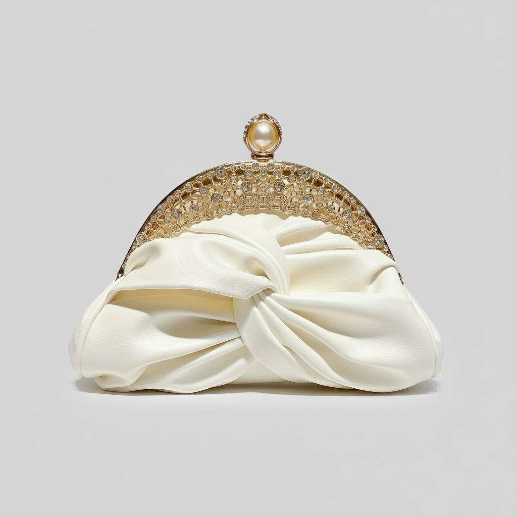 Cream-colored clutch with gold embellishments held by a hand against a light gray background