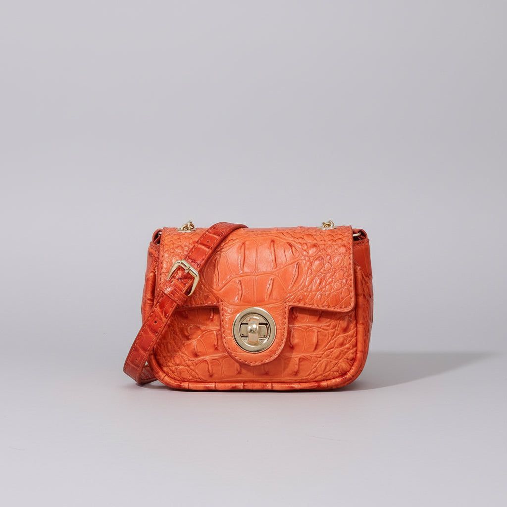 Orange textured handbag on a wooden surface with a dark background