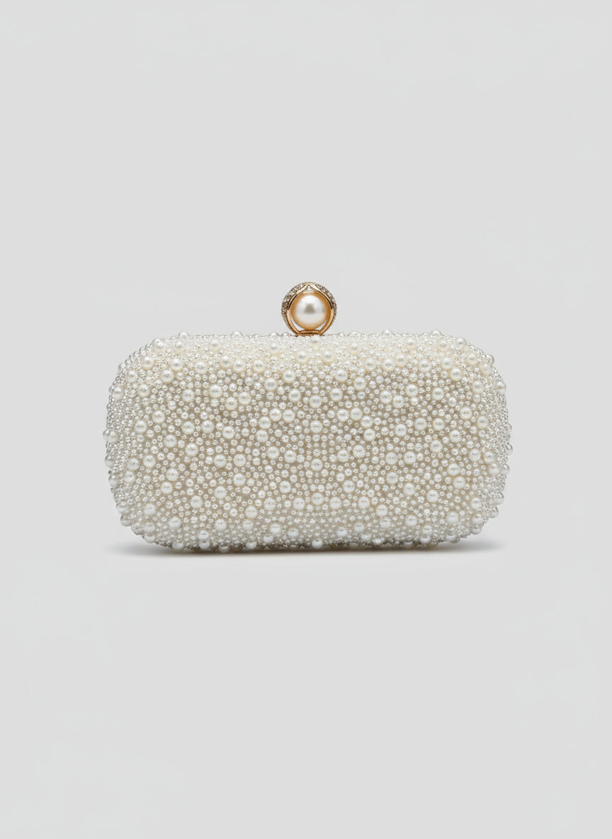 Pearl-handled clutch held by a hand against a light blue tiled wall.