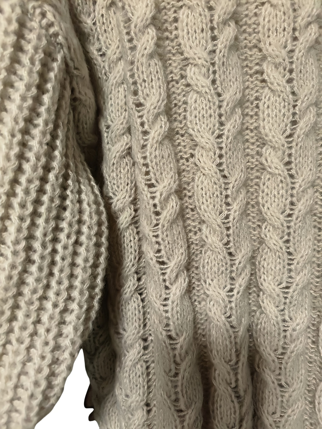 Close-up of a beige knitted sweater with cable pattern