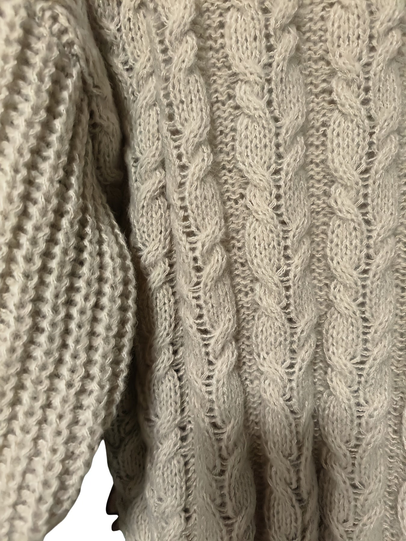Close-up of a beige knitted sweater with cable pattern