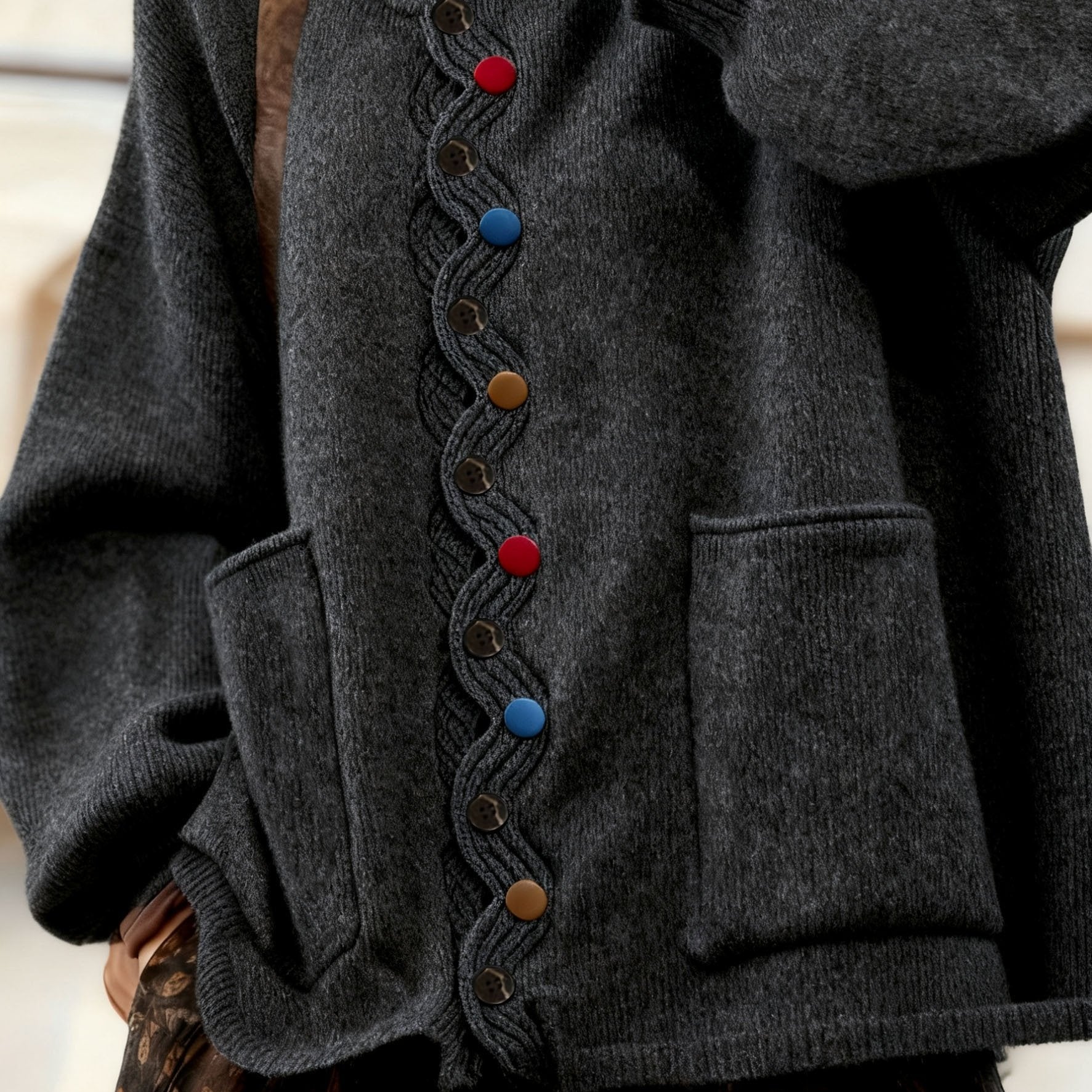 Close-up of a dark gray coat with colorful buttons on a neutral background
