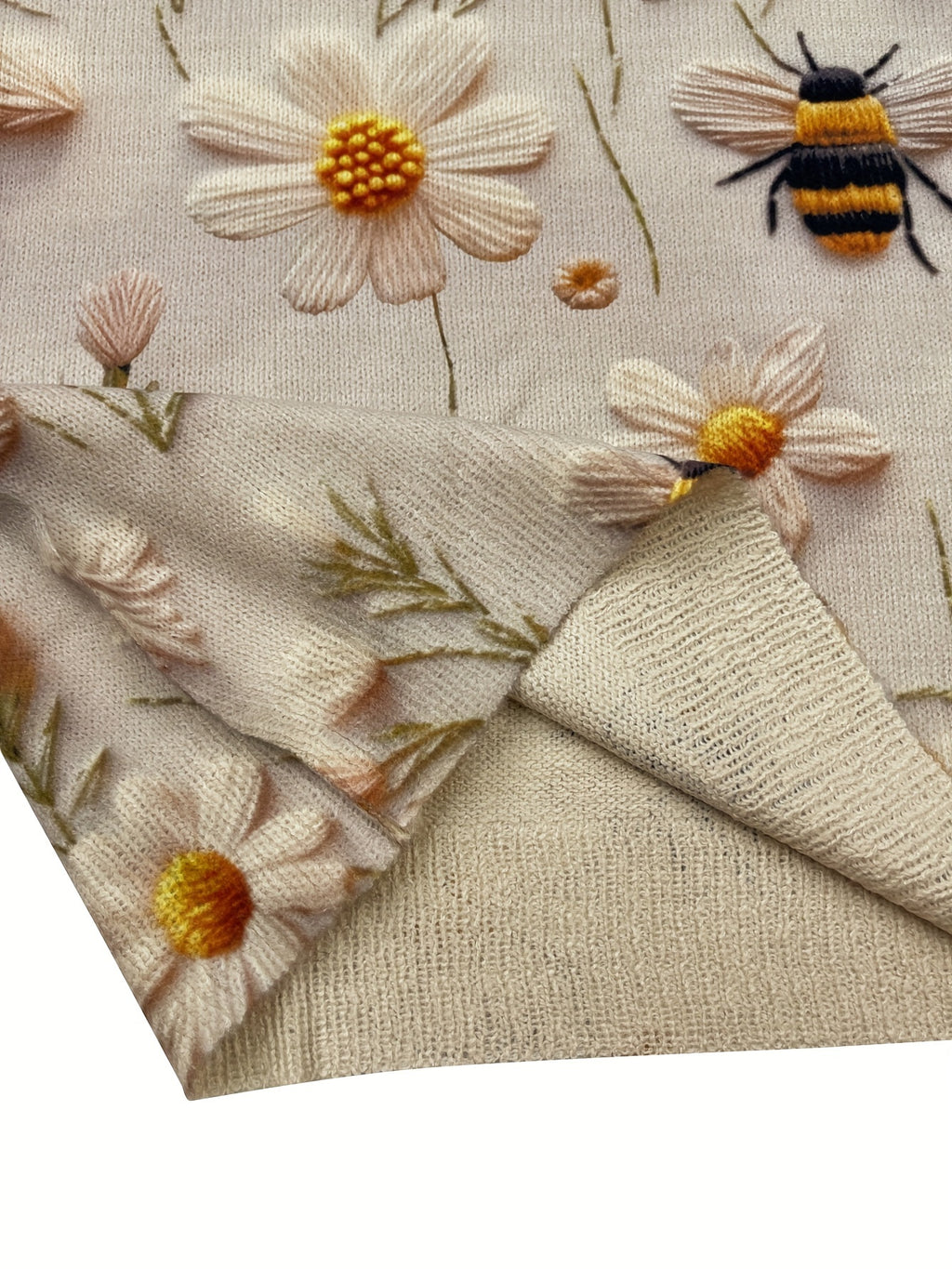 Close-up of embroidered fabric with flowers and a bee on a beige background