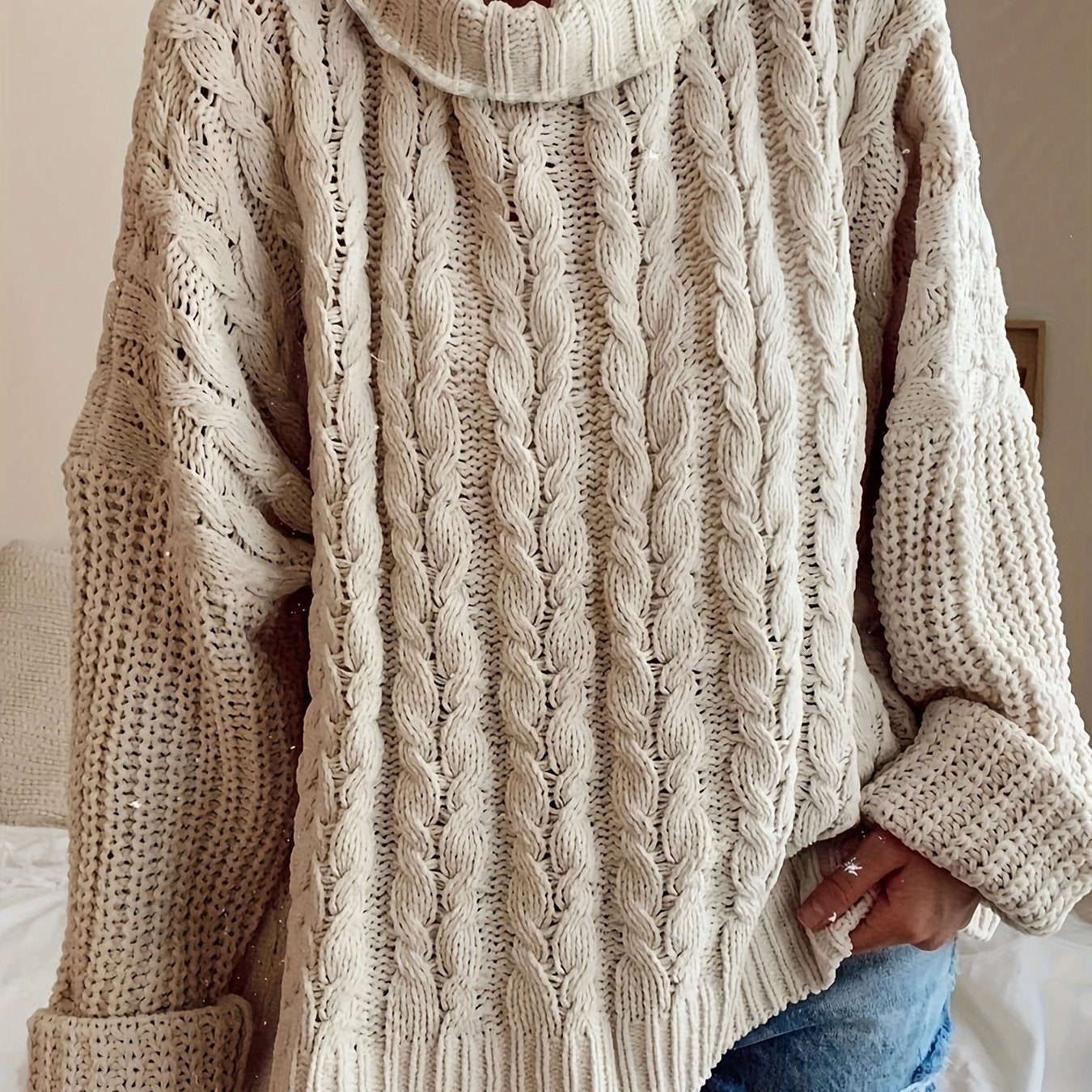 Beige cable knit sweater worn by a person, with a neutral background
