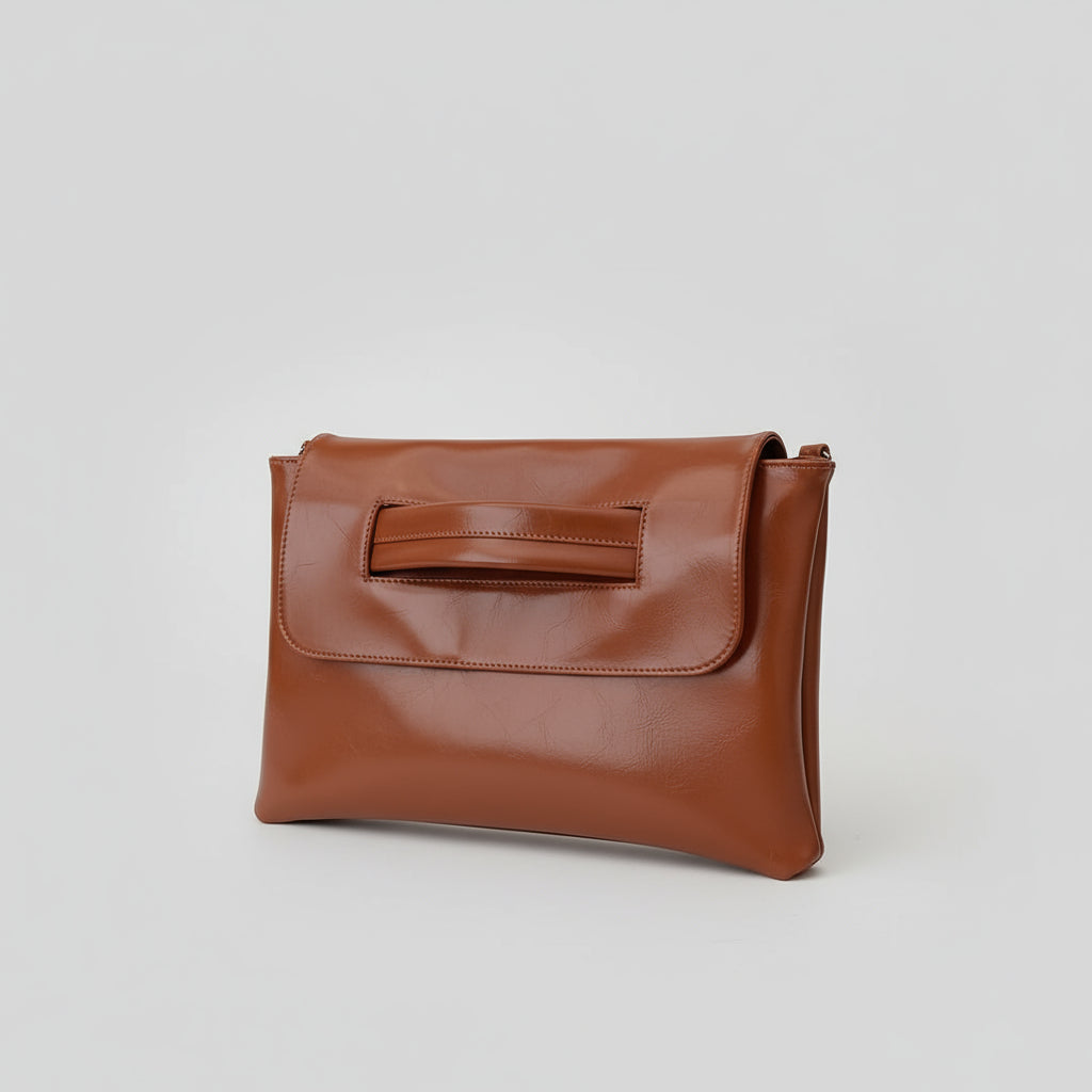 Person holding a brown leather clutch bag in a neutral setting