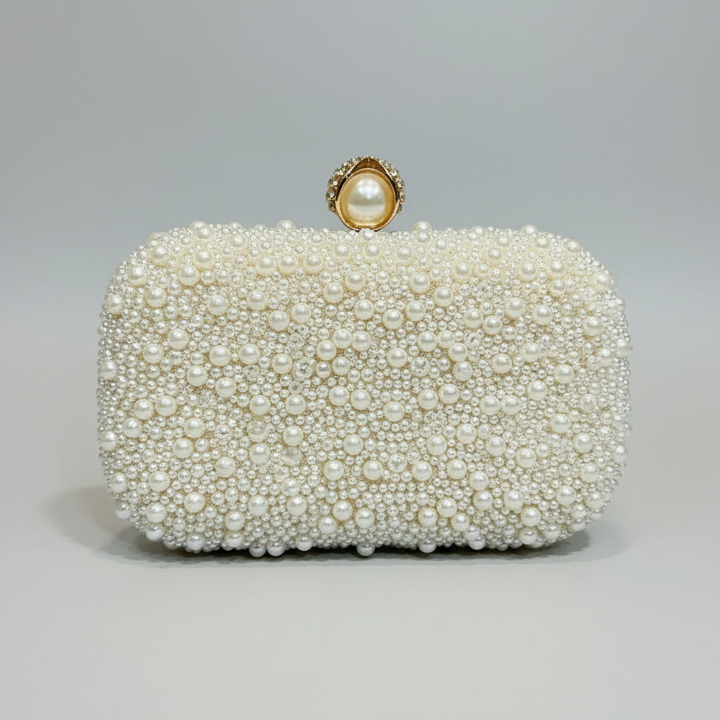 Pearl-handled clutch held by a hand with red nail polish against a neutral background