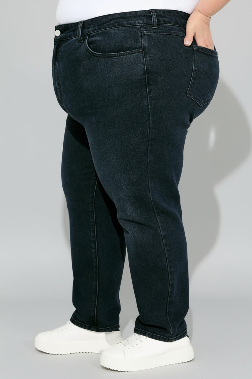 Person wearing dark blue jeans and white sneakers against a light background