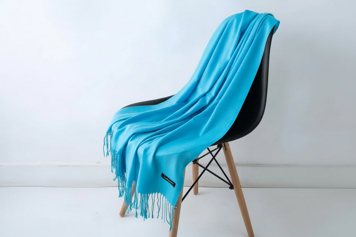 Turquoise blanket draped over a white chair with a plant in the background
