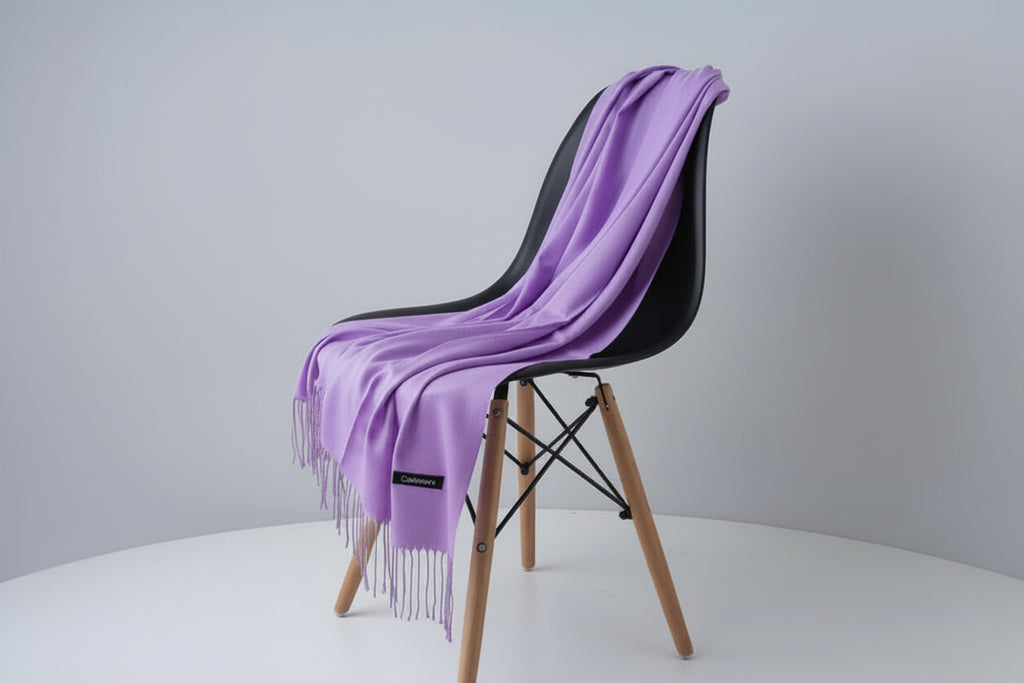 Purple scarf draped over a white chair with a visible brand label, against a light gray background.