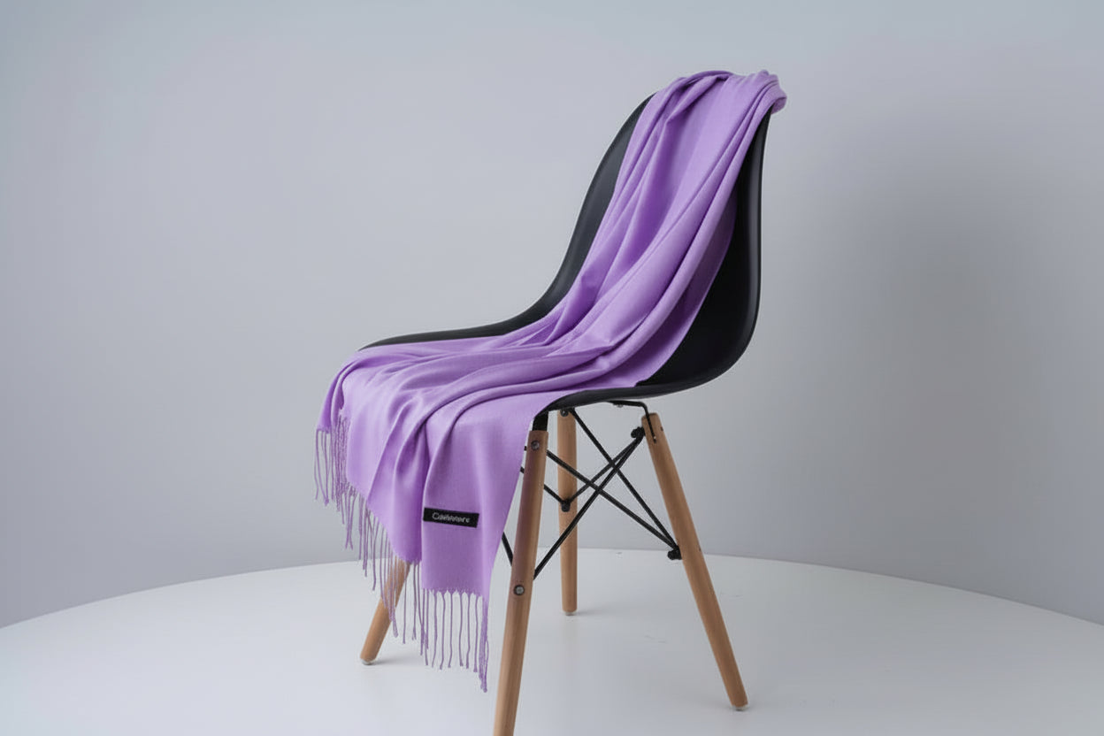 Purple scarf draped over a white chair with a visible brand label, against a light gray background.