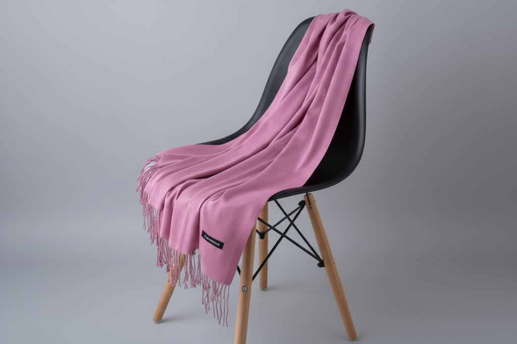 Pink scarf draped over a white chair with a plant in the background